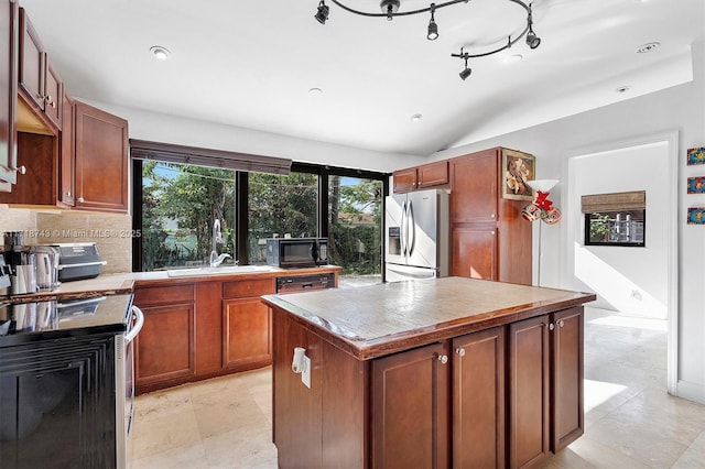 kitchen featuring sink, stainless steel fridge with ice dispenser, backsplash, a kitchen island, and range