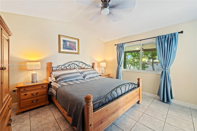 bedroom with a textured ceiling, ceiling fan, light tile patterned flooring, and lofted ceiling