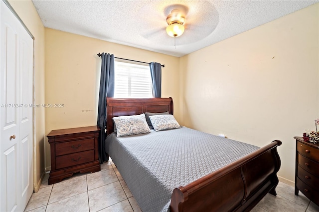 bedroom featuring ceiling fan, light tile patterned floors, a textured ceiling, and a closet