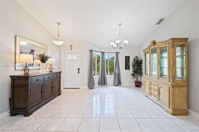 tiled entryway with a notable chandelier, a textured ceiling, and vaulted ceiling