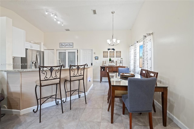 dining area with sink, light tile patterned floors, lofted ceiling, and an inviting chandelier