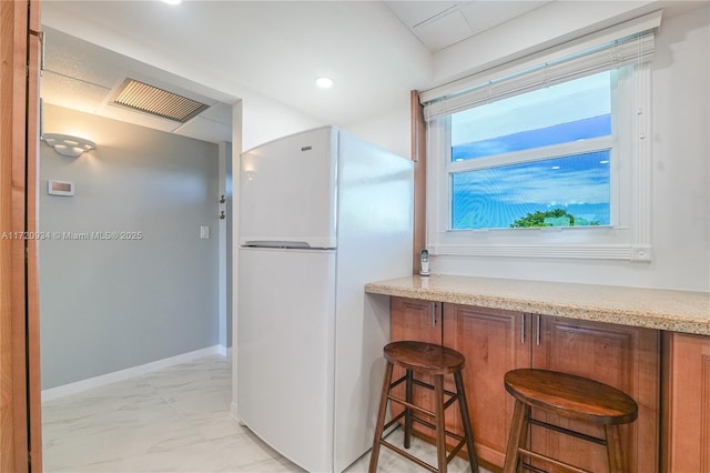 interior space with white fridge and a breakfast bar area