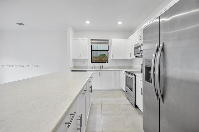 kitchen with white cabinetry, appliances with stainless steel finishes, sink, and light tile patterned floors