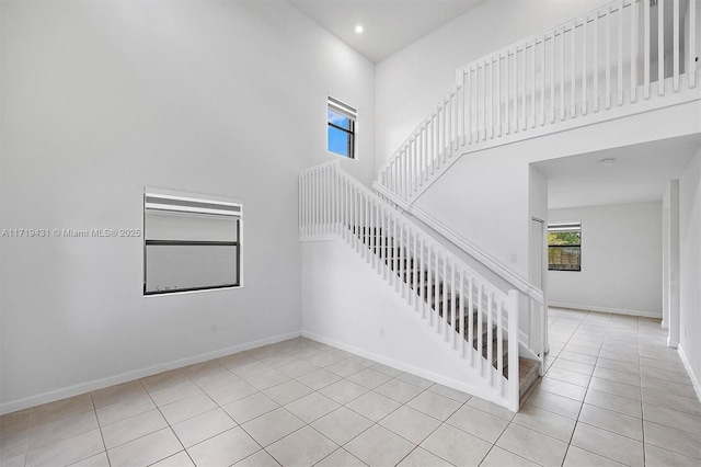 staircase with tile patterned flooring and a towering ceiling