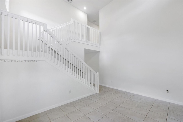 staircase with tile patterned flooring and a high ceiling