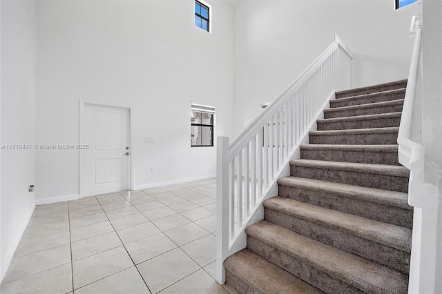 stairs with tile patterned flooring and a high ceiling