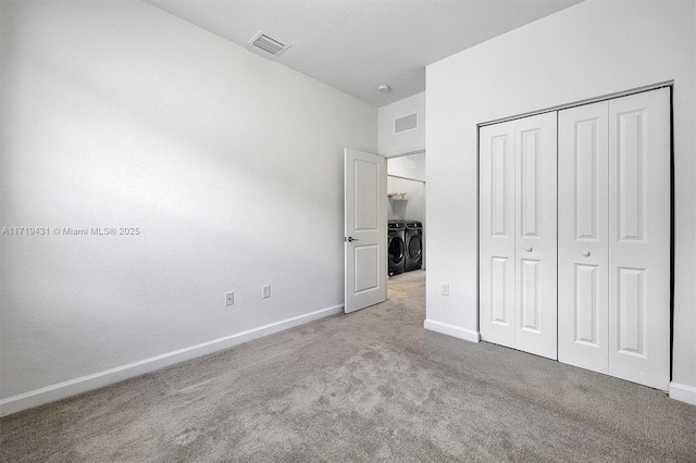 unfurnished bedroom featuring a closet, washing machine and dryer, and light carpet