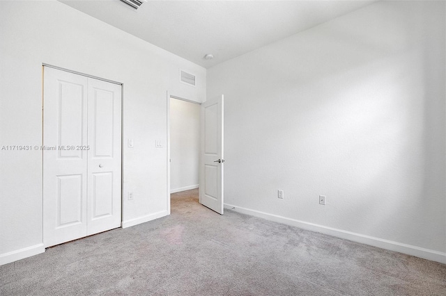 unfurnished bedroom with light colored carpet and a closet