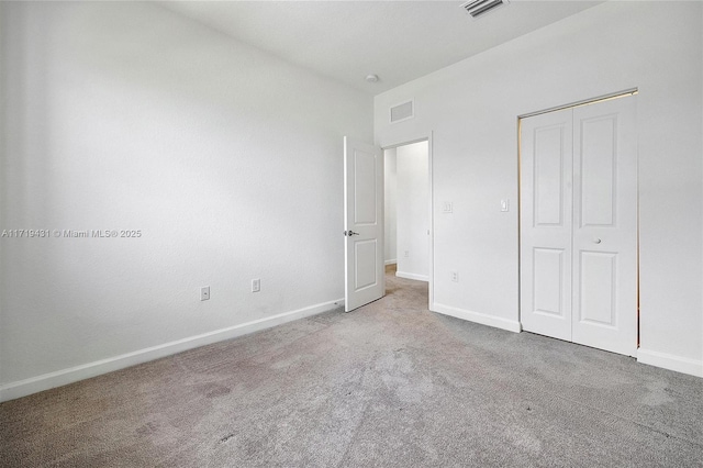 unfurnished bedroom featuring light colored carpet and a closet