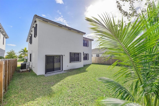 rear view of house with a yard and central AC