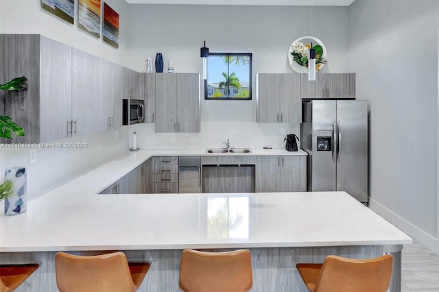 kitchen featuring stainless steel appliances, sink, hanging light fixtures, and a breakfast bar area