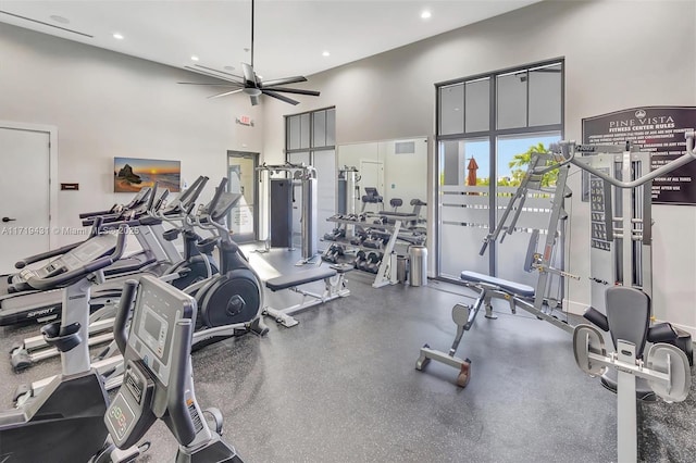 gym featuring a towering ceiling and ceiling fan