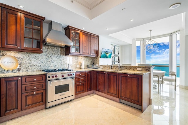 kitchen featuring luxury range, a sink, backsplash, a peninsula, and wall chimney range hood