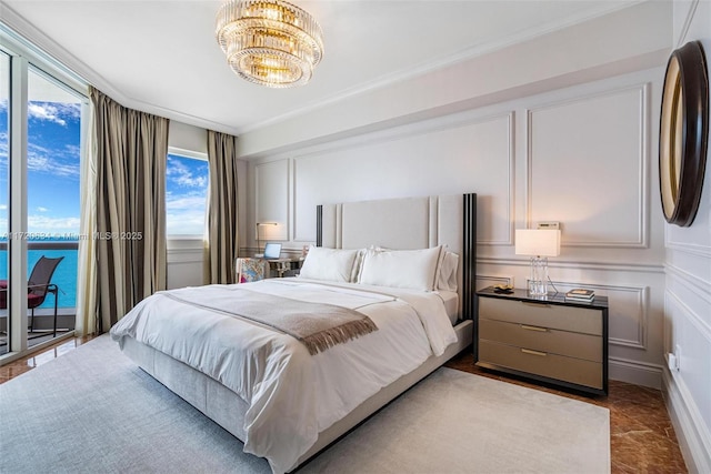 bedroom featuring access to outside, a water view, a chandelier, and ornamental molding