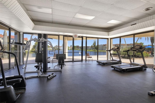 workout area with a paneled ceiling and a water view