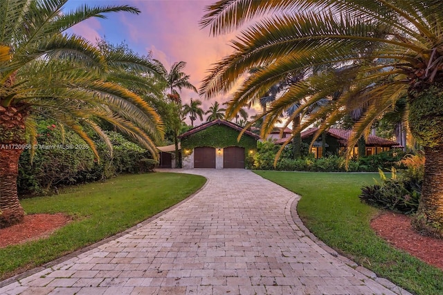 view of front facade featuring an attached garage, a front lawn, and decorative driveway