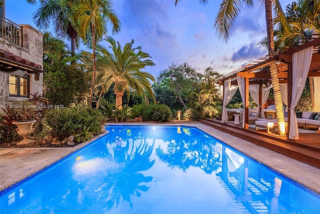 outdoor pool with a deck, a pergola, and an outdoor living space