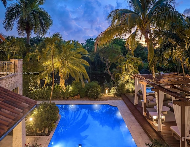 pool at dusk with a patio area, an outdoor pool, and a pergola