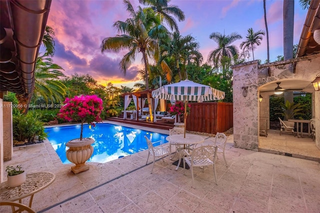 outdoor pool with a patio, fence, and a ceiling fan