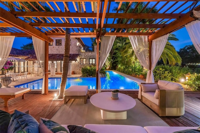 pool at dusk with outdoor lounge area, fence, a pergola, an outdoor pool, and a wooden deck