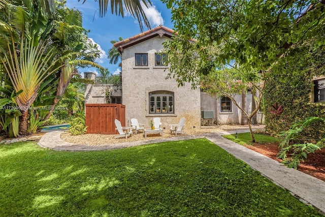 back of house with a fire pit, a yard, and stucco siding