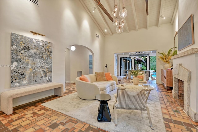 living room with arched walkways, beam ceiling, a fireplace, a high ceiling, and wood ceiling