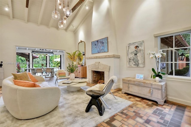 sitting room featuring brick floor, a fireplace, a towering ceiling, baseboards, and beamed ceiling