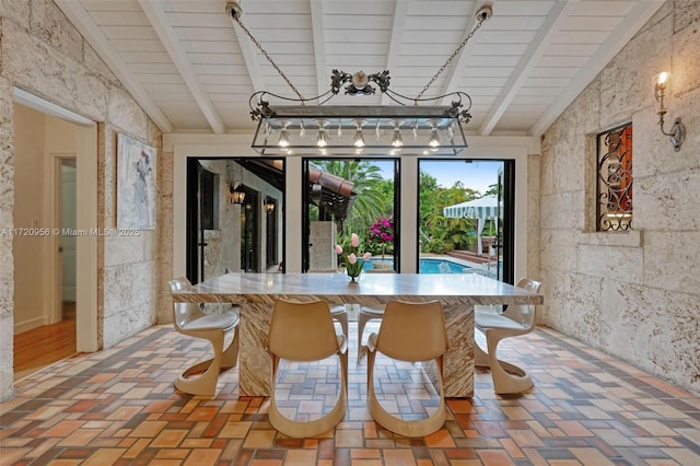 dining space featuring vaulted ceiling with beams and brick floor