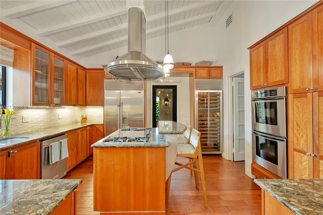 kitchen featuring wine cooler, stainless steel appliances, hanging light fixtures, glass insert cabinets, and a kitchen island