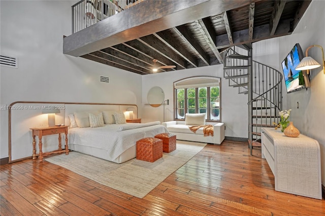 bedroom with baseboards, visible vents, wood finished floors, and beamed ceiling