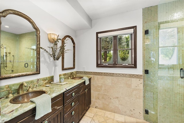 full bathroom featuring stone tile flooring, a sink, tile walls, and a shower stall