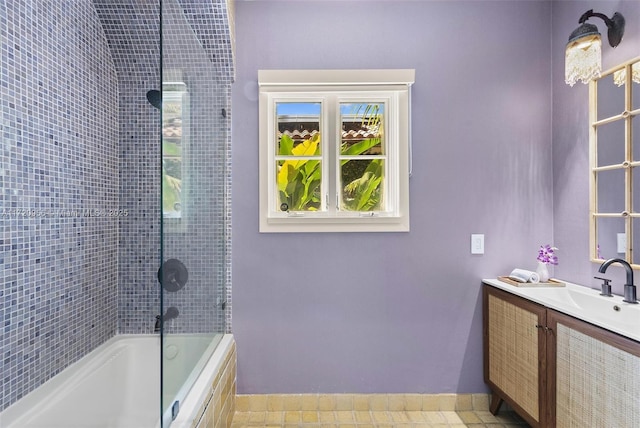 full bath featuring baseboards, tiled shower / bath, and vanity