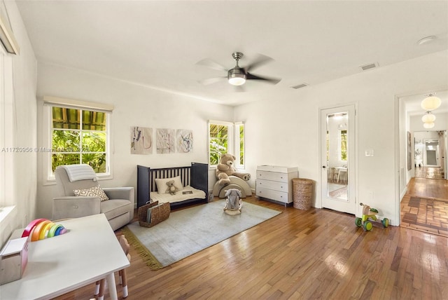 sitting room with ceiling fan, wood finished floors, and visible vents