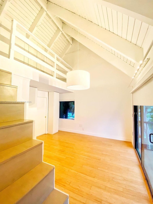 stairs with beam ceiling, hardwood / wood-style flooring, and high vaulted ceiling