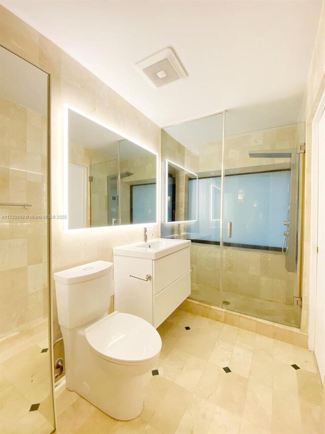 bathroom featuring vanity, toilet, walk in shower, and tile walls