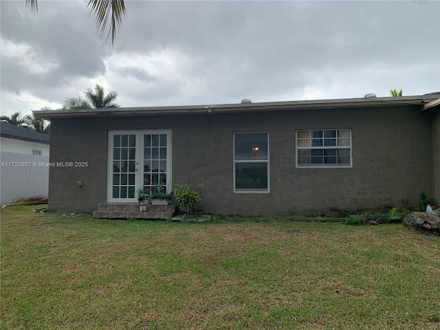 back of property featuring a lawn, stucco siding, and french doors