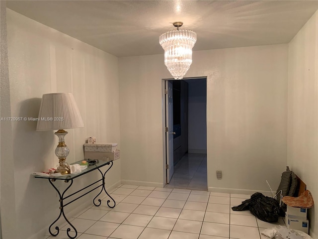 interior space featuring light tile patterned floors, a notable chandelier, and baseboards