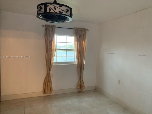 empty room with light tile patterned floors and baseboards