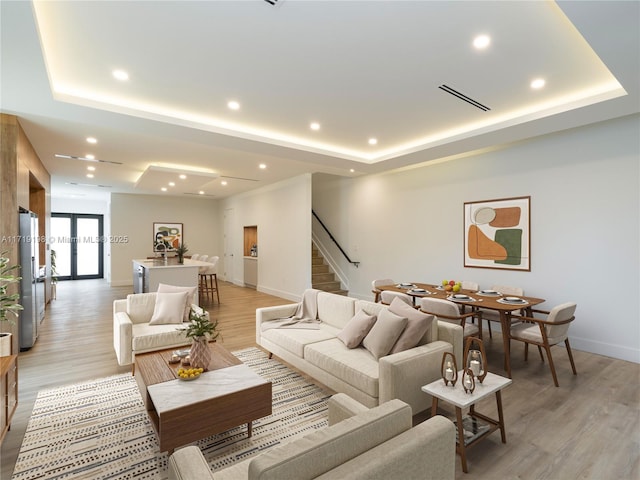 living room featuring light wood-type flooring and a tray ceiling