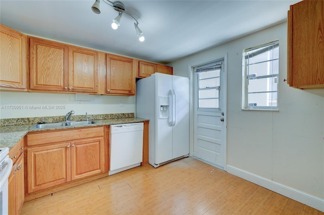 kitchen featuring light wood-type flooring, white appliances, light stone counters, and sink