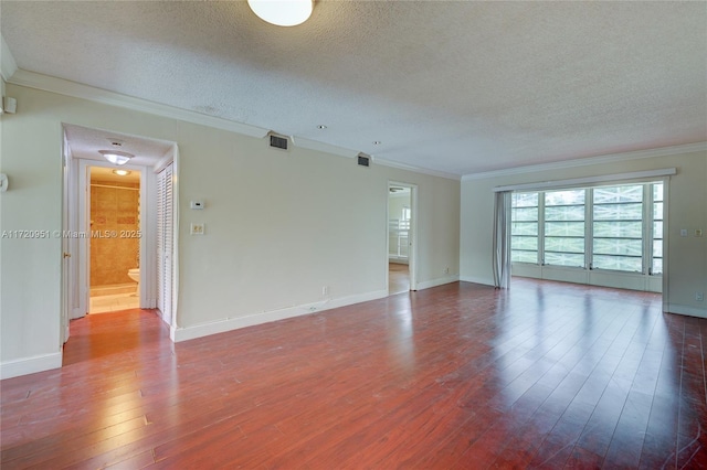 empty room with hardwood / wood-style flooring, a textured ceiling, and ornamental molding