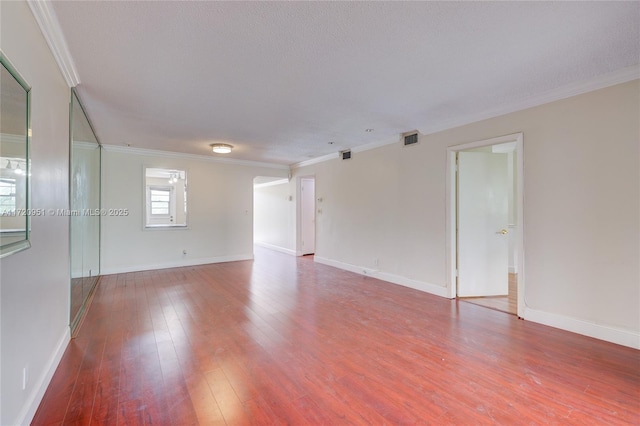 empty room with hardwood / wood-style floors, ornamental molding, and a textured ceiling