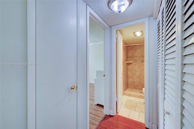 hall with hardwood / wood-style flooring and a textured ceiling