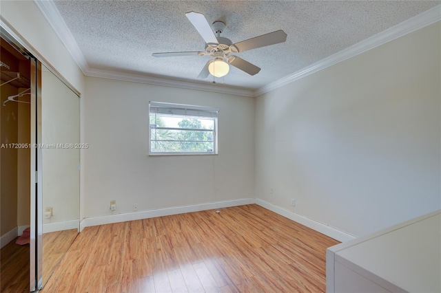 unfurnished bedroom featuring a closet, light hardwood / wood-style flooring, ceiling fan, and crown molding