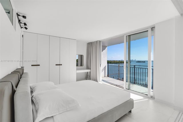 bedroom featuring a water view, a wall of windows, and access to outside