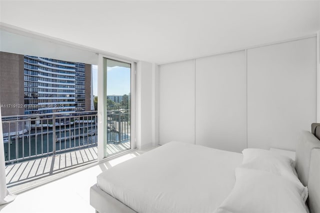 bedroom featuring access to exterior, a water view, and expansive windows