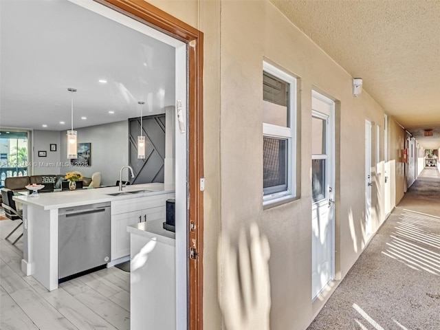 kitchen with dishwasher, sink, a kitchen breakfast bar, kitchen peninsula, and pendant lighting