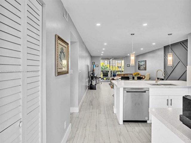 kitchen featuring light stone counters, sink, dishwasher, white cabinets, and hanging light fixtures