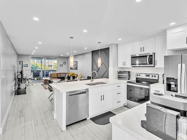 kitchen with sink, white cabinets, stainless steel appliances, and decorative light fixtures