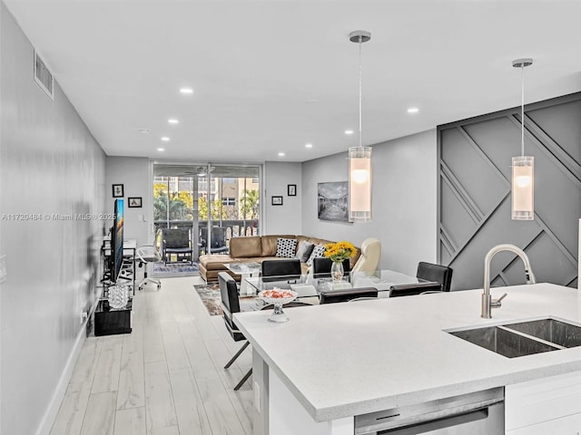 kitchen featuring a kitchen breakfast bar, dishwasher, sink, and decorative light fixtures